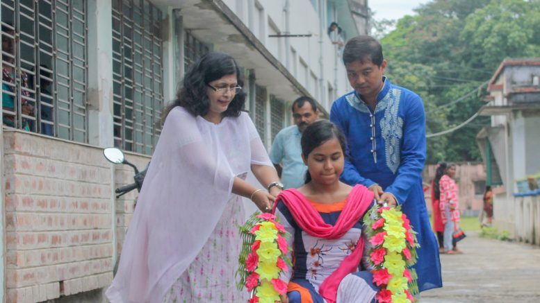 Santipur College Principal Chandrima Bhattacharjee and Non-teaching staff Biswajit Roy take a physically challenged student to classroom on wheelchair